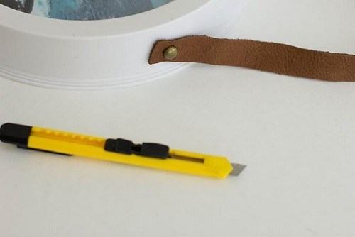 Dùng dao rọc giấy tạo hai lỗ nhỏ trên dây da và hai cạnh của đồng hồ (Nguồn: Internet)