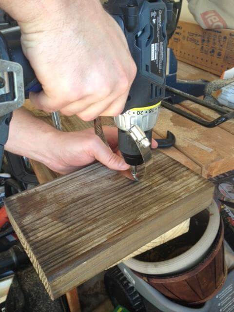 Bắt ốc vít vào lỗ khoan để cố định đai xiết vào tấm gỗ (Nguồn: Internet)