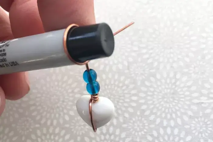 Thêm hạt cườm và quấn đoạn dây thép còn thừa thành một vòng quanh ống bút nhựa hình trụ tròn (Nguồn: Internet)